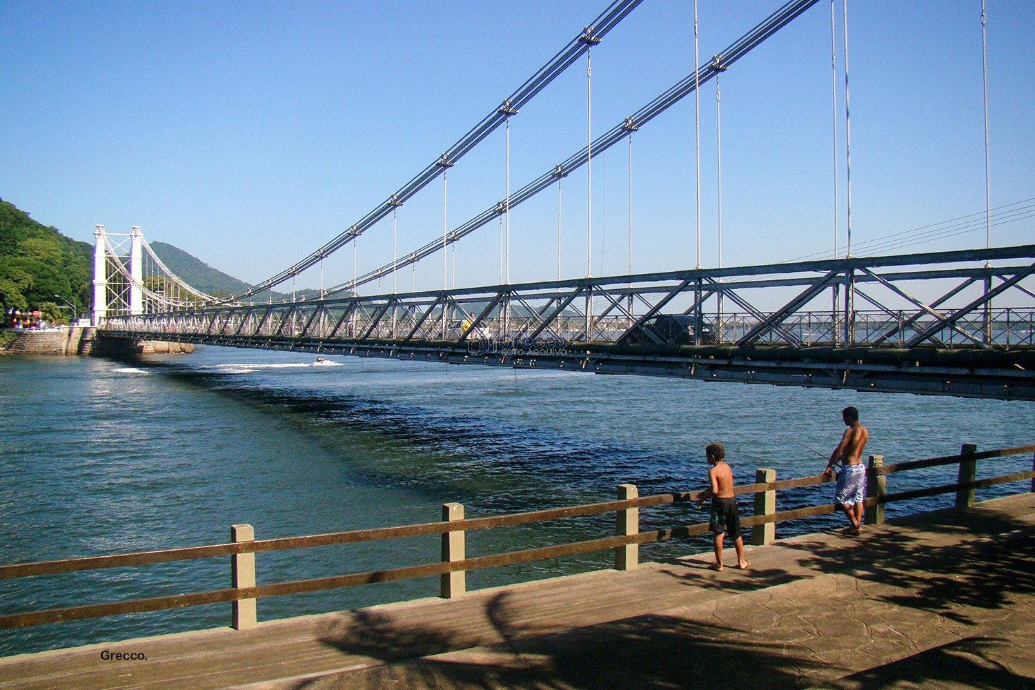 Crianças brincando no Píer dos Pescadores com Ponte Pênsil ao fundo.